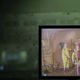 Dressed in contamination suits, three workers are watched by a crane specialist on a video monitor in a control room at the Savannah River Site.